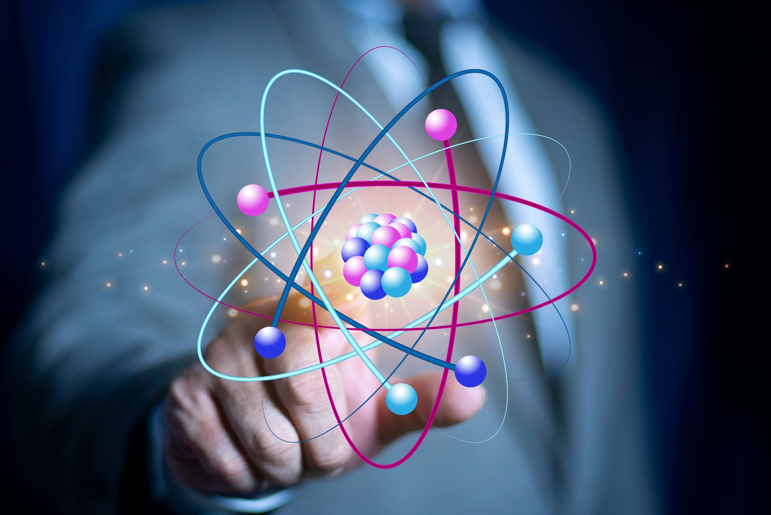 Profissional apontando modelo atômico luminoso, simbolizando radiofármacos e teranóstico na Pós-graduação em Medicina Nuclear.
